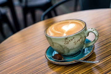 Cup with heart shape in milk froth of coffee latte as background
