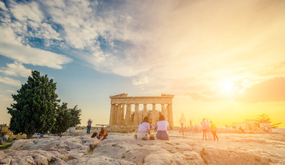 Tourists sitting on stones in front of Parthenon in the evening during sunset time, Athens, Greece....