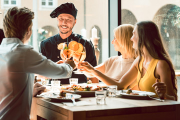 Experienced chef smiling congratulated for the delicious food by four young people at the table of...