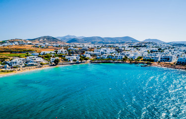 Aerial bird's eye view of a Greek turquoise bay and the whitewashed traditional houses on the coastline and mountains on the background