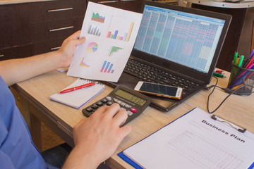 man hand using calculator, accounting concept. Man hands with pencil, notebook and Calculator on wooden table