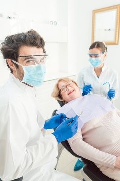 Dentist man in his surgery looking into camera