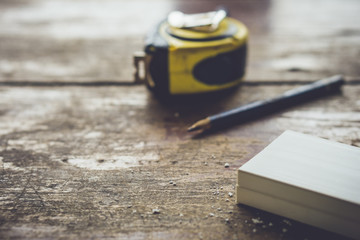 Measuring tape, pencil and rack lying on wooden table. Home renovation with a professional...