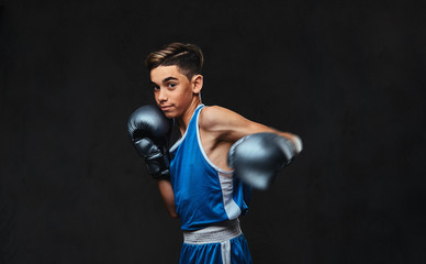 Fototapeta na wymiar Handsome young boxer during boxing exercises, focused on process. Isolated on the dark background.