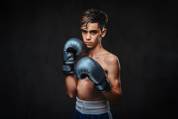 Portrait of a handsome shirtless young boxer wearing gloves. Isolated on a dark background.