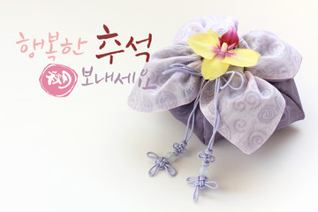 'Happy Chuseok &Hangawi, Translation of Korean Text : Happy Korean Thanksgiving Day' calligraphy and Korean traditional bag &knot of white background.