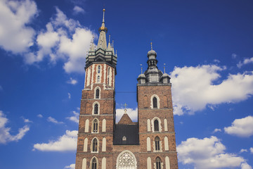 Fototapeta na wymiar catholic church facade with towers in old city district on blue sky background with empty space for copy or text