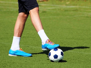 Men's feet and soccer ball on green field