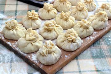 Homemade delicious raw manti (turkish ravioli) on a board sprinkled with flour. Preparation of Manti. Manti, Mantu or Manty Momos, Jiaozi, Dyushbara, Sikkim, Darjeeling