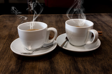 Two coffee cups on wood table in cafe interior