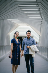 A portrait of a young and loving Chinese couple walking along the airport hallway.. Excited to go on a vacation.