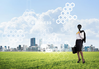 Camera headed woman standing on green grass against modern cityscape