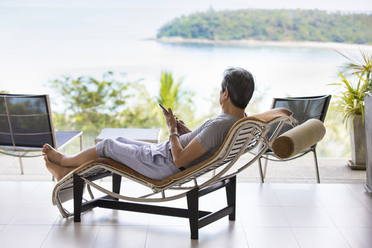 Happy senior man relaxing on balcony - Powered by Adobe