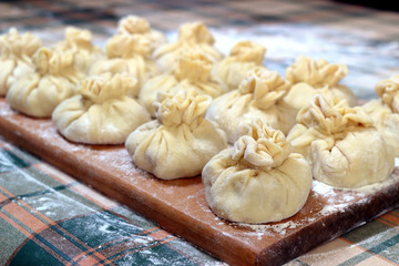 Fototapeta na wymiar Homemade delicious raw manti (turkish ravioli) from dough on a board sprinkled with flour. Preparation of Manti.