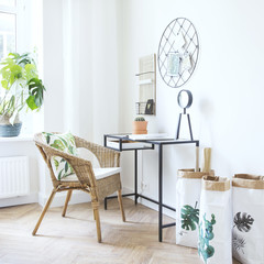 Modern scanidinavian interior of home office with glass table, design clock paper bags and plants. Stylish space with wooden brown parquet.