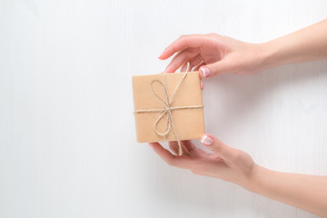 hands of a young girl holding a gift box on a white background