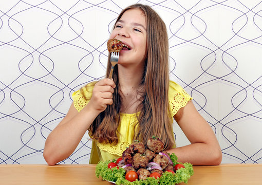 beautiful happy girl eats meatball
