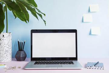 Stylish and creative desk with laptop mock up screen, tropical leaf, office accessories and memo...
