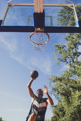 A Men Shooting at Basketball Hoop