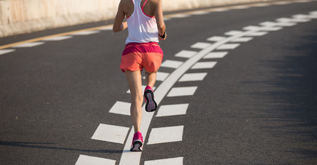Healthy lifestyle fitness woman running on highway road.