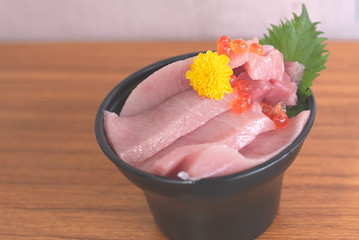 Otoro and  Ikura on a black cup on a wooden table.