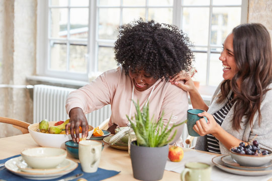 Zwei Freundinnen lachen beim Frühstück essen