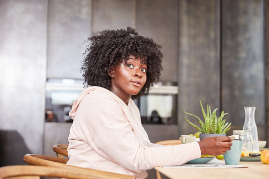 Junge afrikanische Frau sitzt am Tisch in Küche