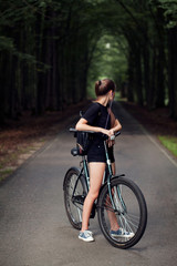 girl with a backpack riding a bicycle in a park.