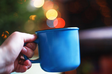 a cup in the hand . Christmas bokeh
