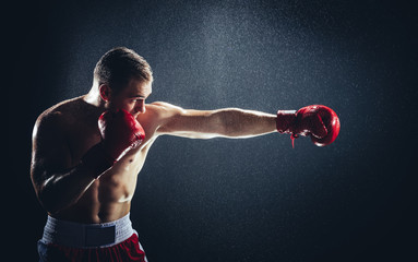 Boxer striking a blow in the rain. - obrazy, fototapety, plakaty