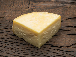 Piece of homemade cheese on the wooden background.