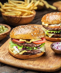 Hamburgers and French fries on the wooden tray.