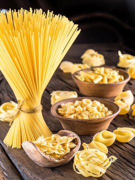 Different pasta types on wooden table.