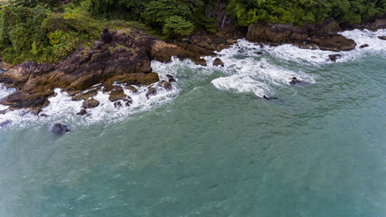 Aerial view of a rocky and green beach shore.