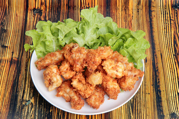 Crispy deep fried chicken served with green oak .