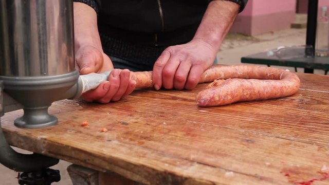 Butcher is stuffing pig intestine with minced meat to make sausages. Fill up pig intestines to make sausage with machine for handmade sausages.