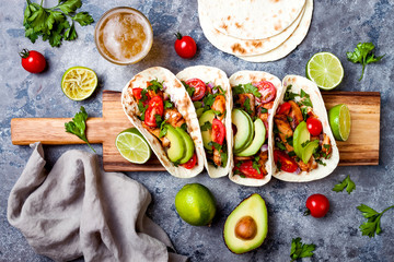 Mexican grilled chicken tacos with avocado, tomato, onion on rustic stone table. Recipe for Cinco de Mayo party. Top view, overhead, flat lay. © sveta_zarzamora