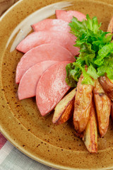 Roasted potatoes with ham slices close up