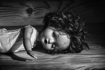 Old broken doll on a wooden table.