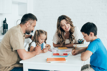 parents helping children with homework at table at home