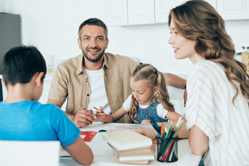 parents helping children with homework at table at home