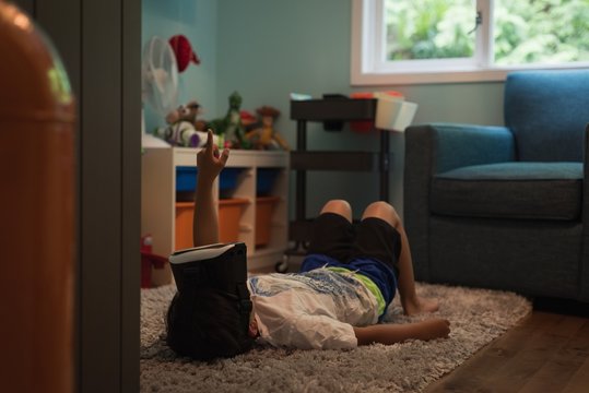 Boy using virtual reality headset while lying on rug at home