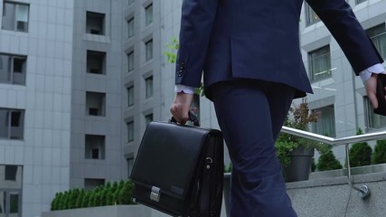 Successful male politician going upstairs with briefcase and phone, businessman