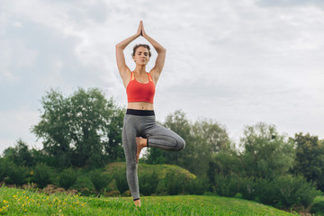 Red sport top. Athletic woman wearing bright red sport top doing yoga being fond of gymnastics and...