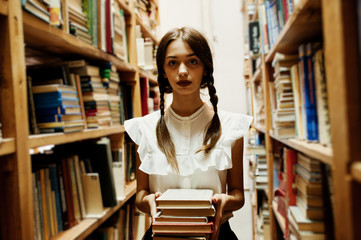 Girl with pigtails in white blouse at old library.