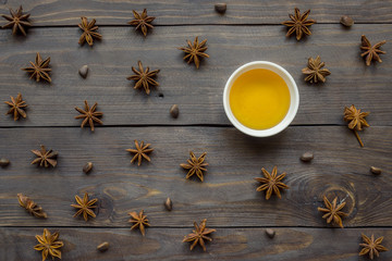 Liquid honey in a plate and star anise on a Dark wooden background. the concept of the starry night sky