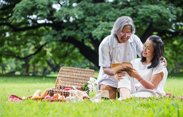 happy senior couple reading books, after retirement in the park,spending time and relaxing time concept..