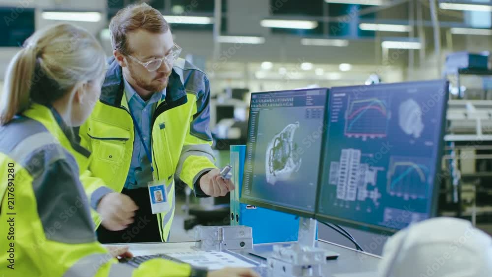Poster At the Factory: Male Mechanical Engineer Holds Component while Female Chief Engineer Work on Personal Computer, They Discuss Details of the 3D Engine Model Design.