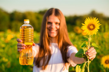 Young woman in white holding bottle of oil in sunflower field - Powered by Adobe