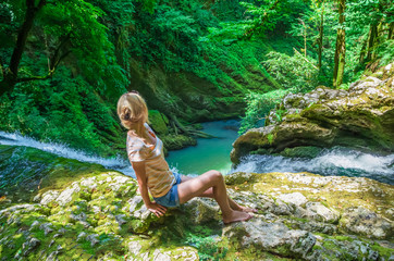beautiful girl sits on top of a waterfall and admires a beautiful view, Georgia
